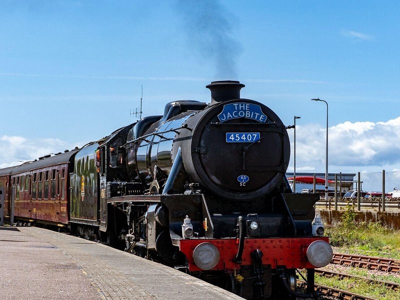 Locomotive 45407 with The Jacobite headboard at a station platform