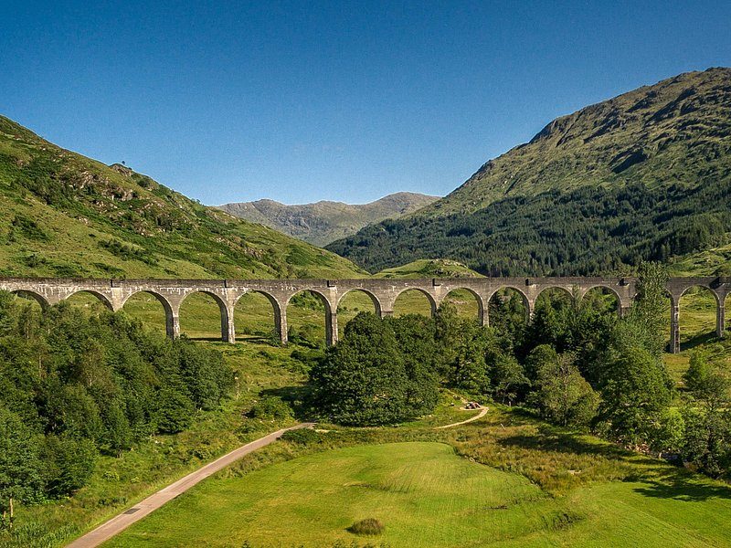 The empty viaduct spanning a green glen, a path running up the valley floor